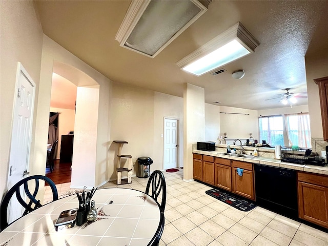 kitchen featuring black appliances, tile countertops, brown cabinetry, and a sink