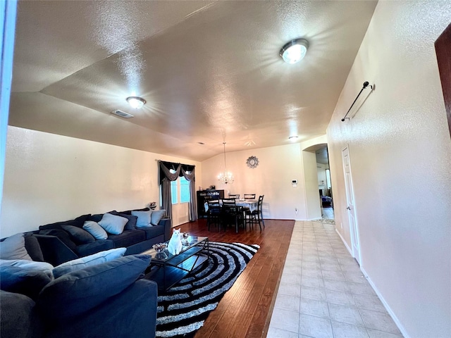 living area featuring visible vents, lofted ceiling, wood finished floors, arched walkways, and a textured ceiling