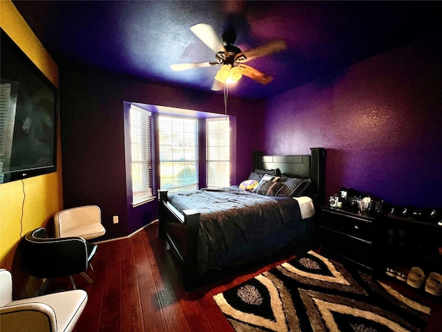 bedroom with a ceiling fan, baseboards, and wood-type flooring