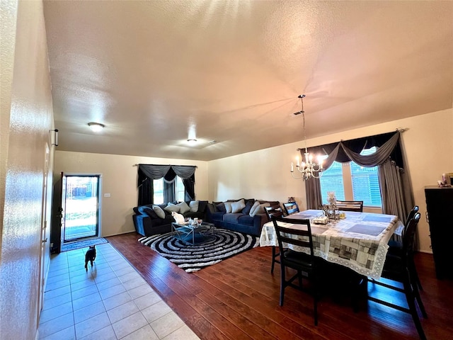 dining space with a textured ceiling, an inviting chandelier, and wood finished floors