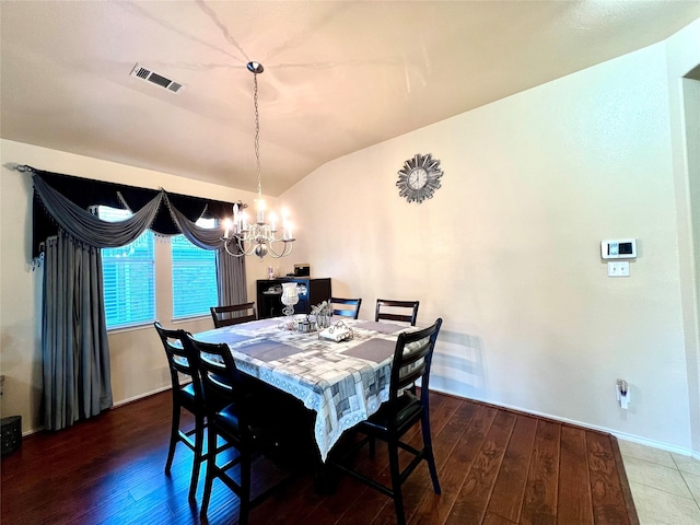 dining area with visible vents, lofted ceiling, a notable chandelier, and wood finished floors