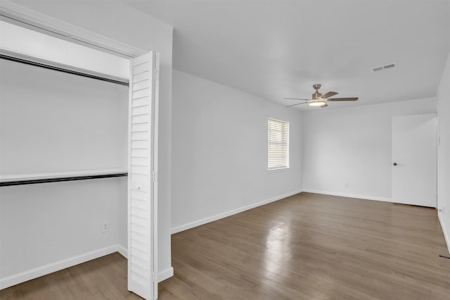 unfurnished bedroom featuring visible vents, baseboards, a closet, ceiling fan, and wood finished floors