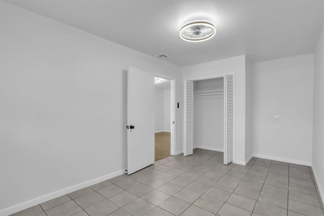 unfurnished bedroom with a closet, light tile patterned floors, baseboards, and visible vents