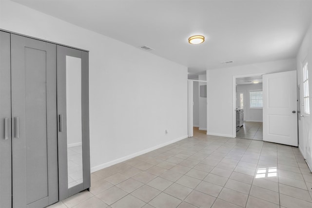 unfurnished bedroom with light tile patterned floors, visible vents, and baseboards