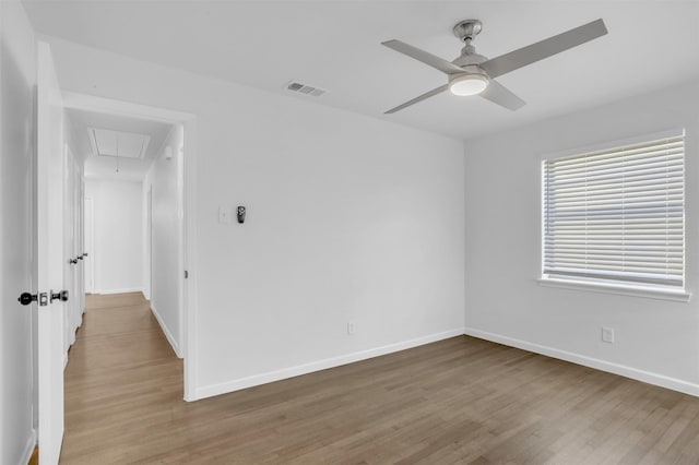 unfurnished room with visible vents, baseboards, attic access, and wood finished floors