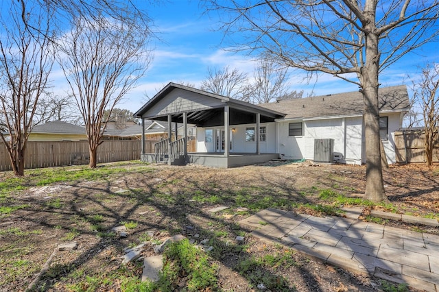 rear view of house featuring a shingled roof, covered porch, fence, and brick siding