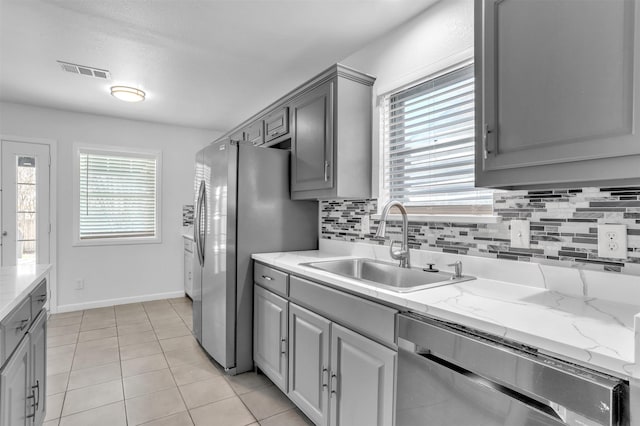 kitchen featuring a sink, tasteful backsplash, appliances with stainless steel finishes, and gray cabinetry