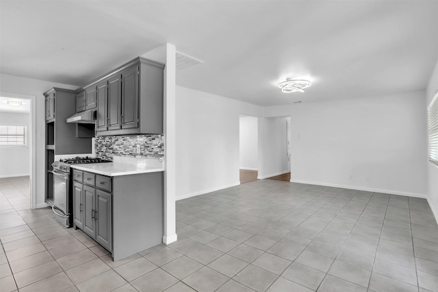 kitchen featuring light tile patterned floors, light countertops, stainless steel gas stove, and gray cabinetry