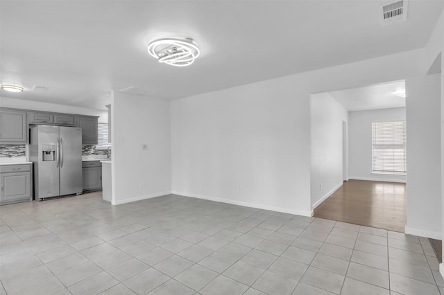 unfurnished living room with light tile patterned floors, baseboards, and visible vents