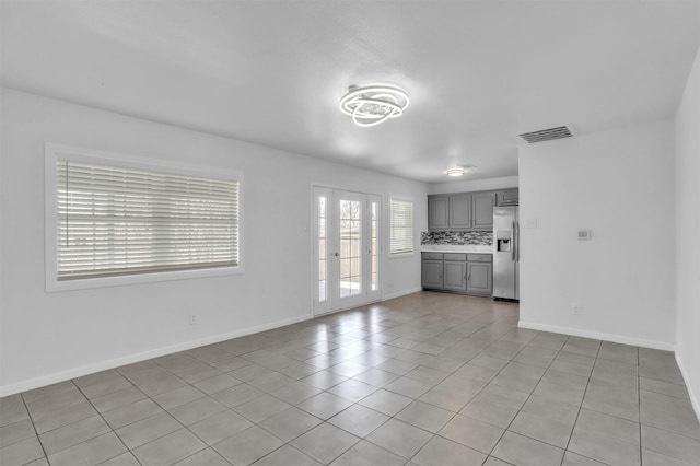 unfurnished living room with light tile patterned floors, visible vents, and baseboards