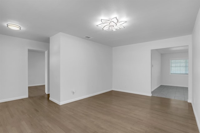 unfurnished room featuring visible vents, baseboards, and wood finished floors