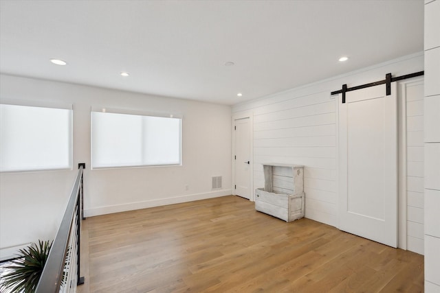 8917 Random Rd, Fort Worth, TX 76179 - unfurnished room with visible vents, a barn door, light wood-style floors, and recessed lighting