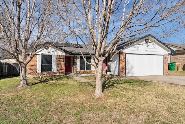 single story home with a front lawn, fence, concrete driveway, brick siding, and solar panels