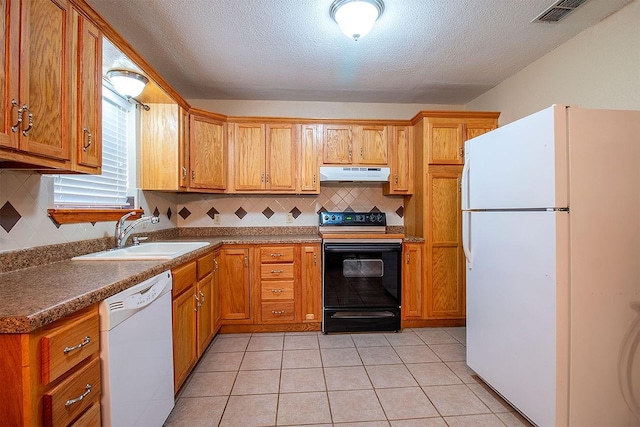 kitchen featuring visible vents, a sink, under cabinet range hood, white appliances, and light tile patterned flooring