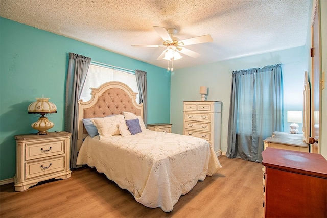 bedroom featuring baseboards, a textured ceiling, light wood-type flooring, and a ceiling fan