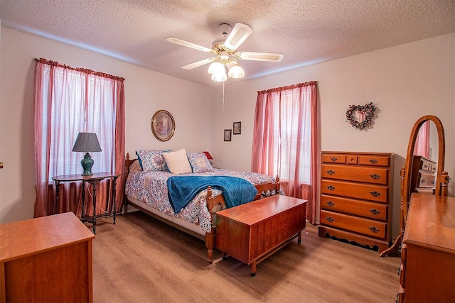 bedroom with ceiling fan, a textured ceiling, and light wood-style flooring