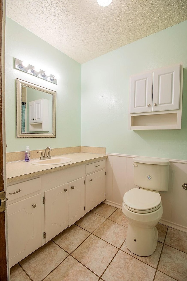 bathroom with tile patterned flooring, toilet, a textured ceiling, and vanity