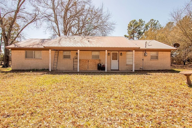 rear view of house with metal roof, a yard, and brick siding