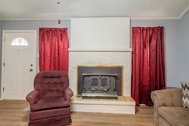 interior space with a fireplace, a textured ceiling, wood finished floors, and crown molding