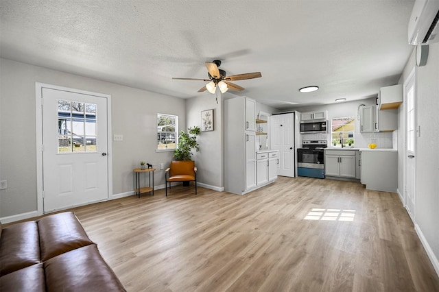 88 Live Oak St, Alvarado, TX 76009 - unfurnished living room featuring light wood-style flooring, a wall unit AC, ceiling fan, and a wealth of natural light
