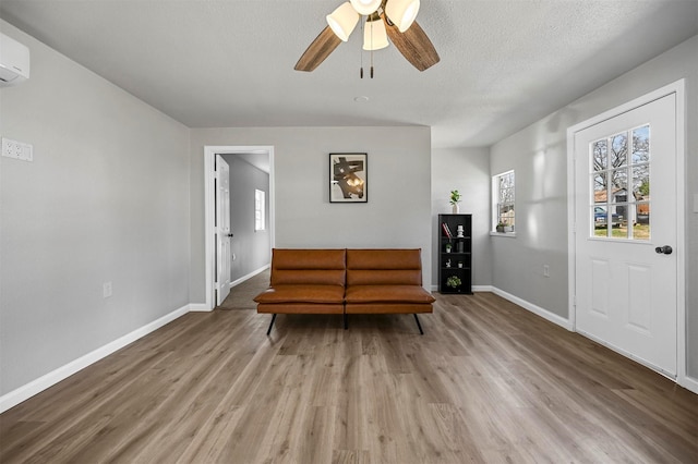 88 Live Oak St, Alvarado, TX 76009 - living area featuring baseboards, an AC wall unit, ceiling fan, a textured ceiling, and wood finished floors