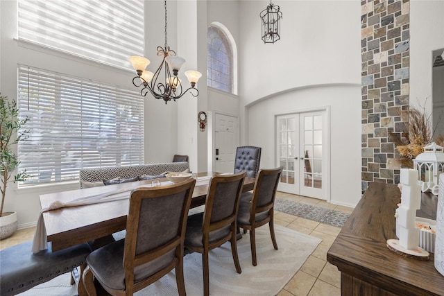 dining area featuring an inviting chandelier, light tile patterned floors, baseboards, and a towering ceiling