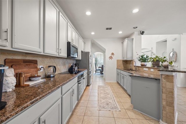 kitchen featuring light tile patterned floors, visible vents, a sink, stainless steel appliances, and tasteful backsplash