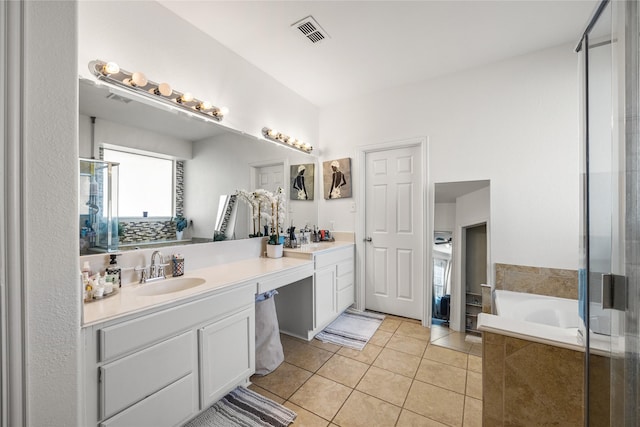 bathroom featuring visible vents, double vanity, a bath, tile patterned floors, and a sink