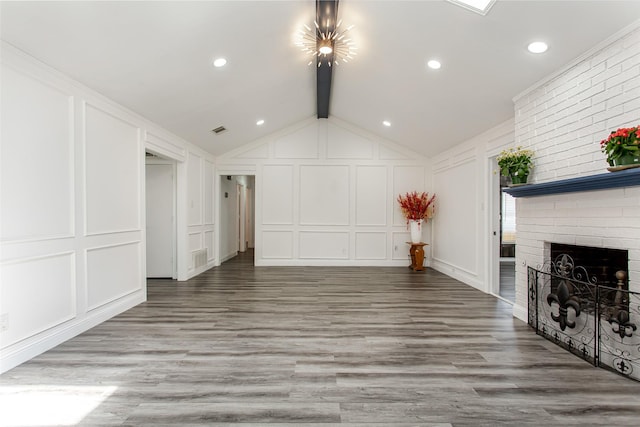 unfurnished living room with a brick fireplace, wood finished floors, vaulted ceiling with beams, and a decorative wall