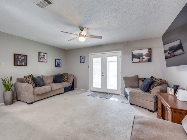 living area featuring visible vents, carpet floors, french doors, a textured ceiling, and a ceiling fan