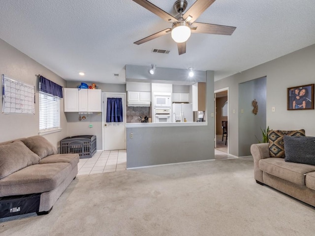 living room with visible vents, light carpet, a textured ceiling, and a ceiling fan