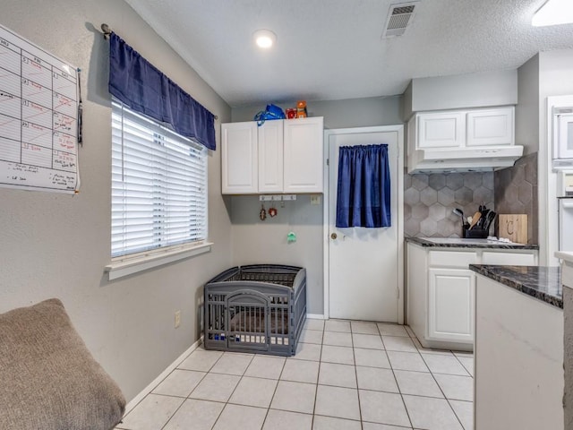 kitchen with under cabinet range hood, visible vents, white cabinetry, and light tile patterned floors