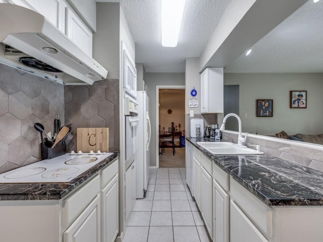 kitchen featuring white appliances, light tile patterned floors, a sink, decorative backsplash, and under cabinet range hood