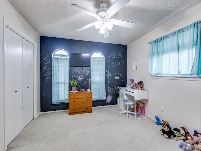 interior space with a textured ceiling, carpet, a wealth of natural light, and ceiling fan