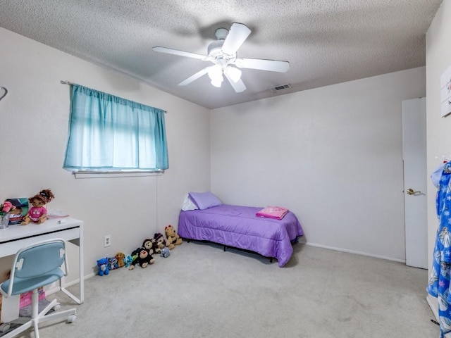 carpeted bedroom featuring visible vents, a textured ceiling, and a ceiling fan