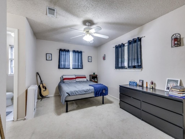 carpeted bedroom featuring visible vents, baseboards, a textured ceiling, and a ceiling fan