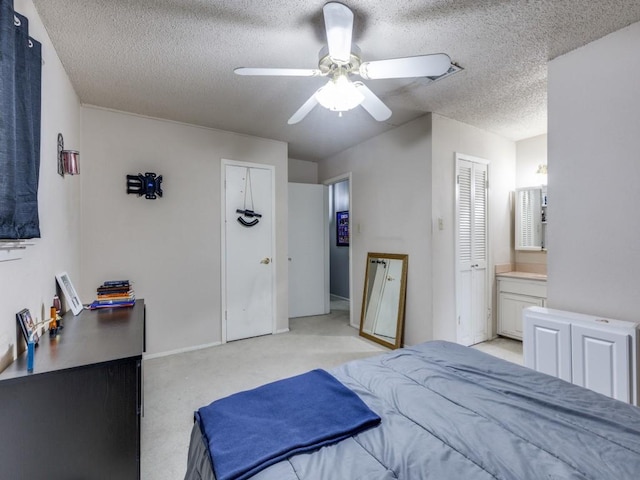 bedroom with connected bathroom, light carpet, a textured ceiling, and a ceiling fan