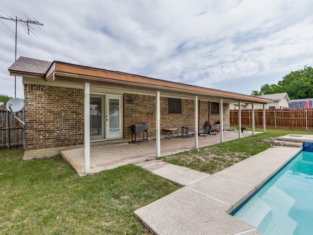 rear view of house with a fenced in pool, a fenced backyard, a lawn, a patio area, and brick siding