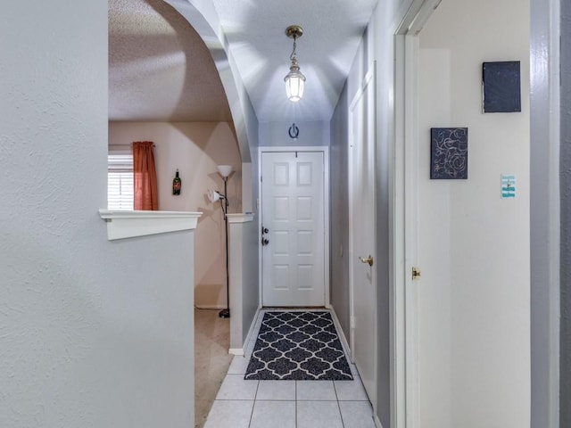 doorway to outside with light tile patterned flooring, baseboards, and a textured ceiling