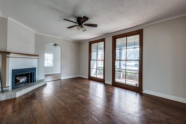 unfurnished living room featuring ceiling fan, ornamental molding, a tile fireplace, hardwood / wood-style flooring, and a textured ceiling