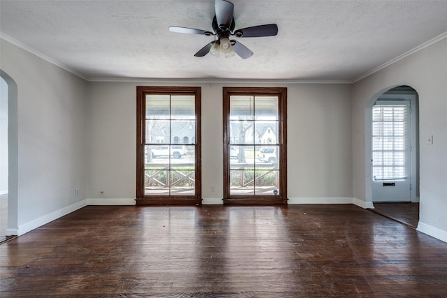 unfurnished room with arched walkways, a textured ceiling, baseboards, and wood finished floors