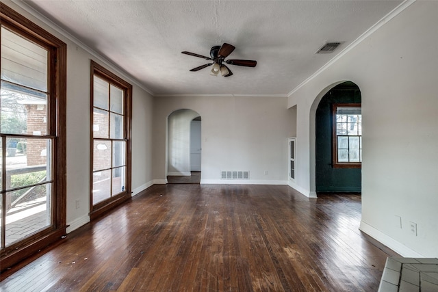 empty room with arched walkways, visible vents, dark wood-type flooring, and ceiling fan