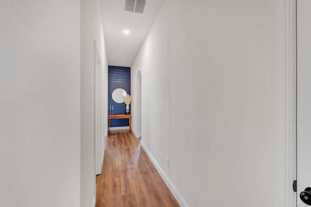 hall featuring visible vents, baseboards, and light wood-style flooring