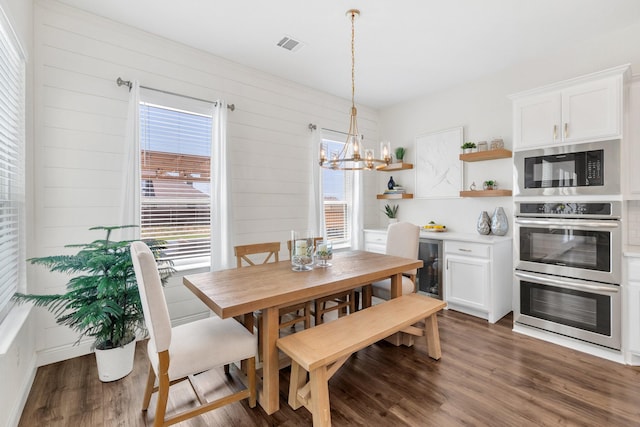 dining area featuring beverage cooler, a notable chandelier, visible vents, and wood finished floors