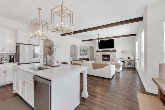 kitchen with ceiling fan with notable chandelier, stainless steel dishwasher, freestanding refrigerator, arched walkways, and a sink