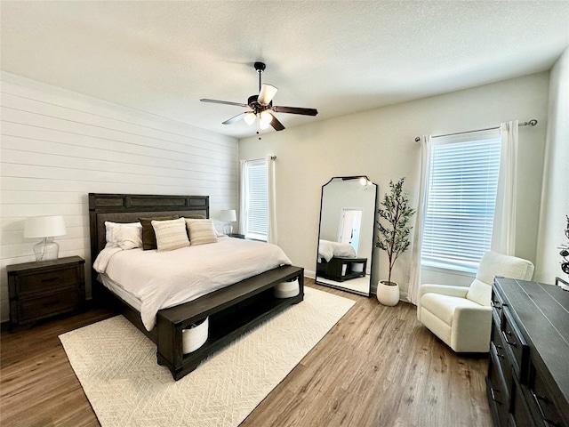 bedroom with ceiling fan, wood finished floors, and a textured ceiling