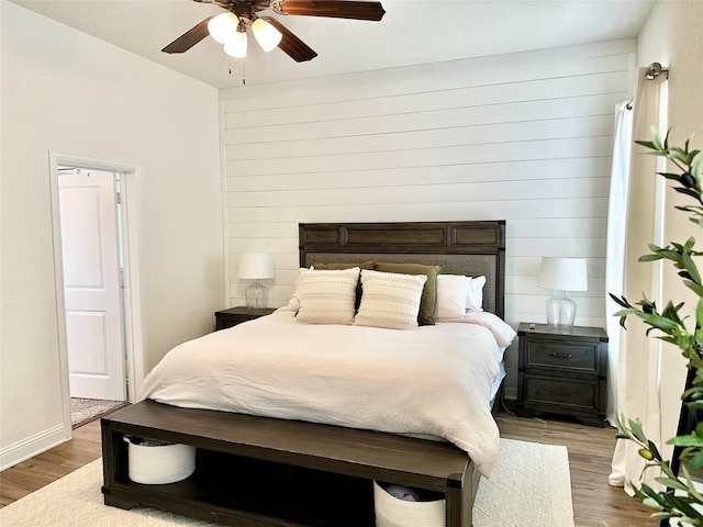 bedroom featuring baseboards, wood finished floors, and a ceiling fan