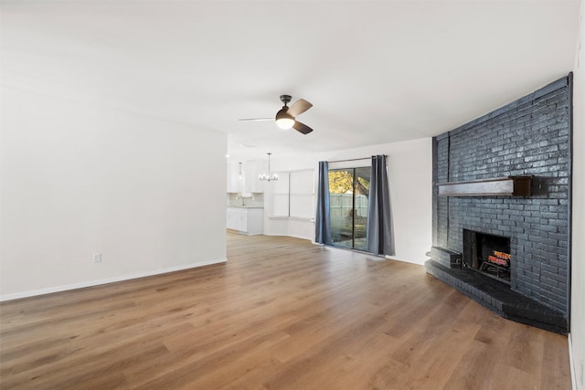 unfurnished living room with a sink, wood finished floors, a fireplace, baseboards, and ceiling fan