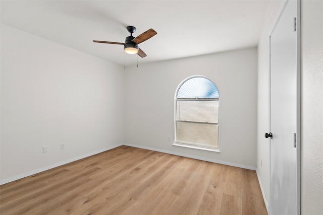 spare room featuring baseboards, light wood-style floors, and ceiling fan
