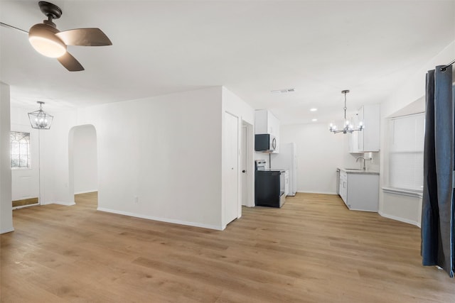 unfurnished living room featuring visible vents, ceiling fan with notable chandelier, light wood-style flooring, arched walkways, and a sink